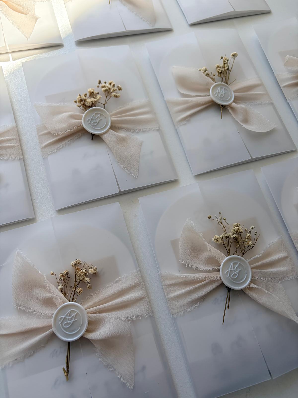 White wedding invitations with decorative bows and seals on a white background